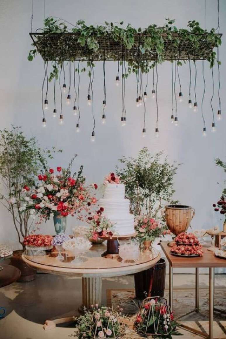 2. Decoração para mesa de bolo em casamento em casa com bastante flores e pendentes minimalistas – Foto: Pinterest