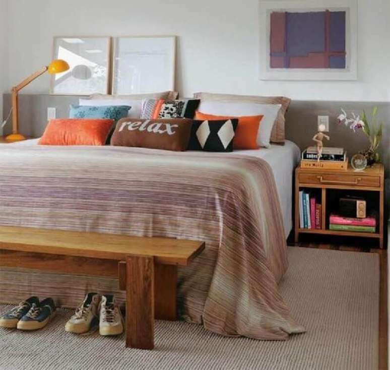 78. Modelo de criado mudo de madeira para quarto de casal com muitas almofadas e luminária amarela – Foto: Pinterest