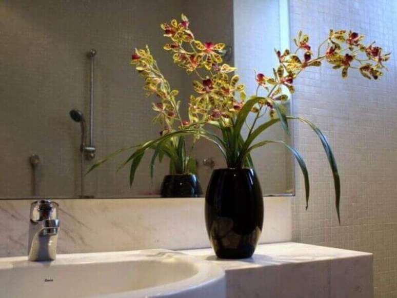 2 -Orqu&iacute;dea em vaso preto decora o ambiente do banheiro.