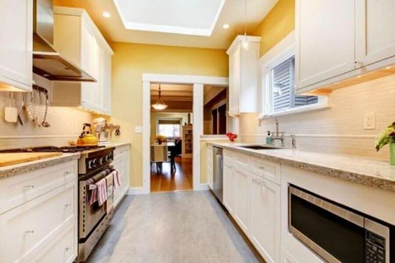 41. Cozinha corredor com paredes amarelas e armários brancos – Foto: Pinterest