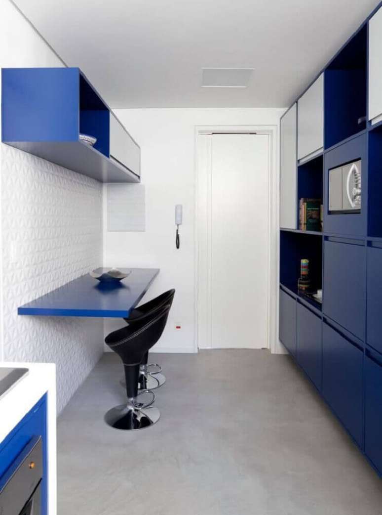 23. Decoração com armário de cozinha corredor azul e banquetas pretas – Foto: Tria Arquitetura