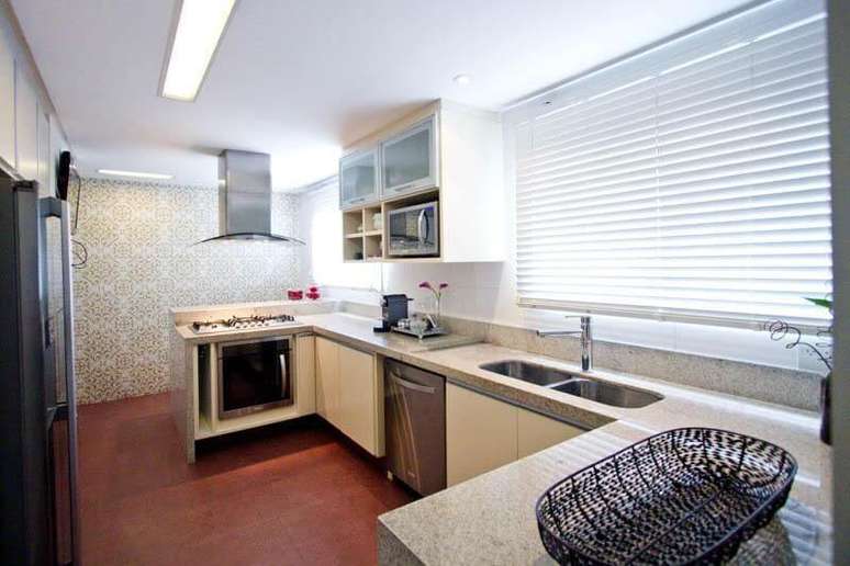 28. Cozinha estilo corredor com bancada de granito claro combinando com os arm&aacute;rios. Projeto de Codecorar