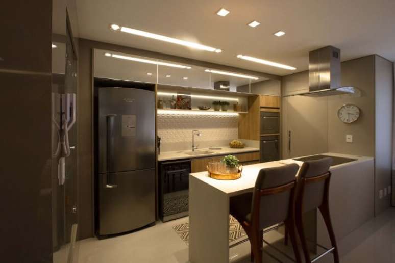 43. Cozinha americana com revestimento 3D em parte da parede com iluminação embutida. Projeto de Marina Turnes