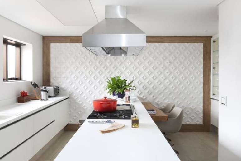 44. Cozinha branca com revestimento 3D em toda a parede com borda de madeira. Projeto de Patricia Bergantin