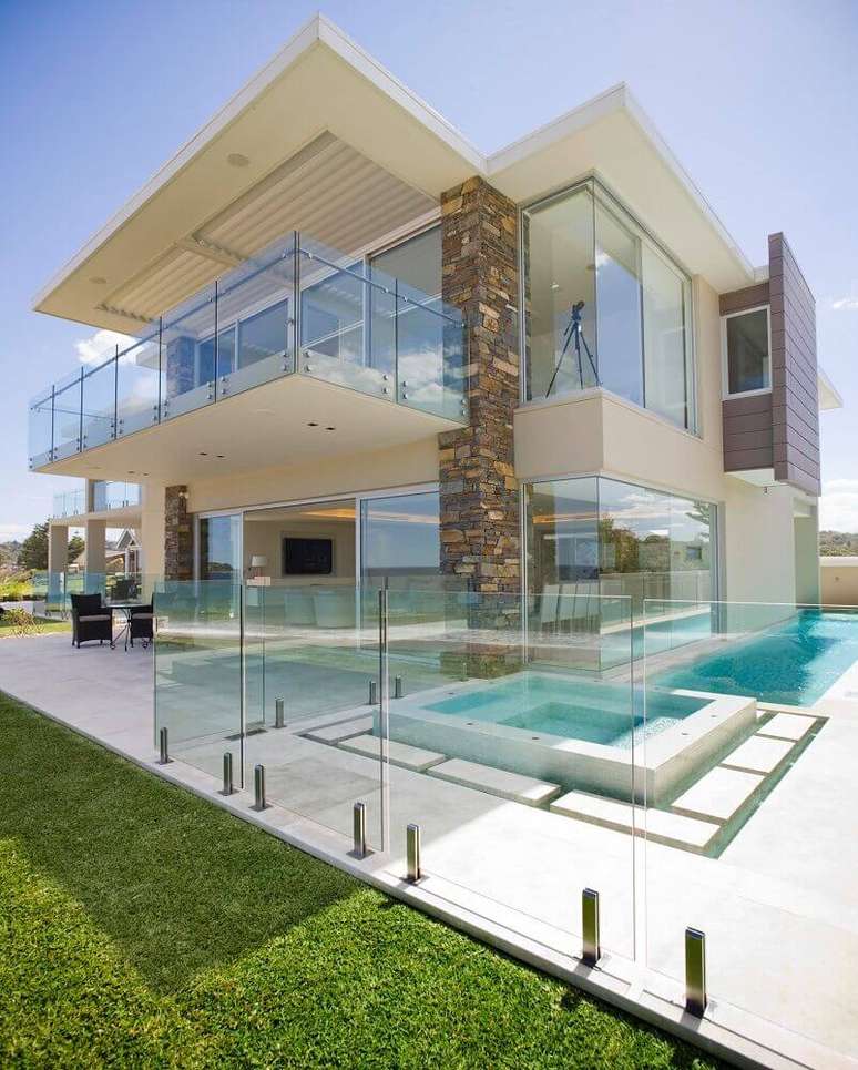 2. Casa moderna com guarda corpo de vidro por toda a sacada e entorno da área de piscina – Foto: Architizer