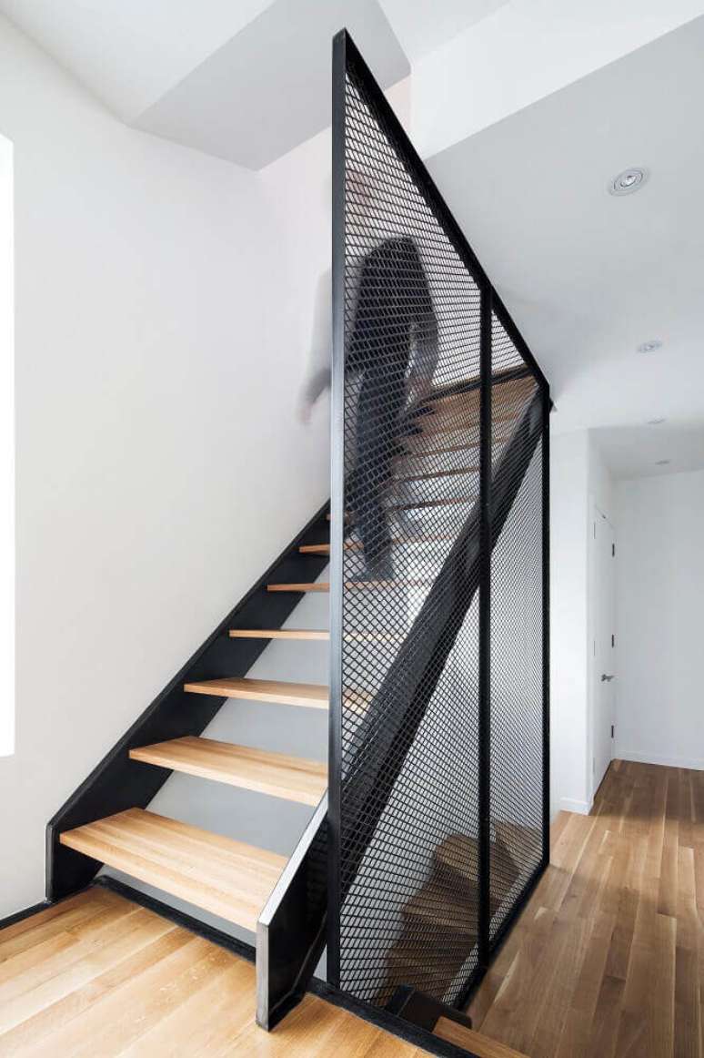 59. Ambiente com estilo moderno com escada de madeira e guarda-corpo feito com uma grade de ferro pintado de preto – Foto: ArchDaily
