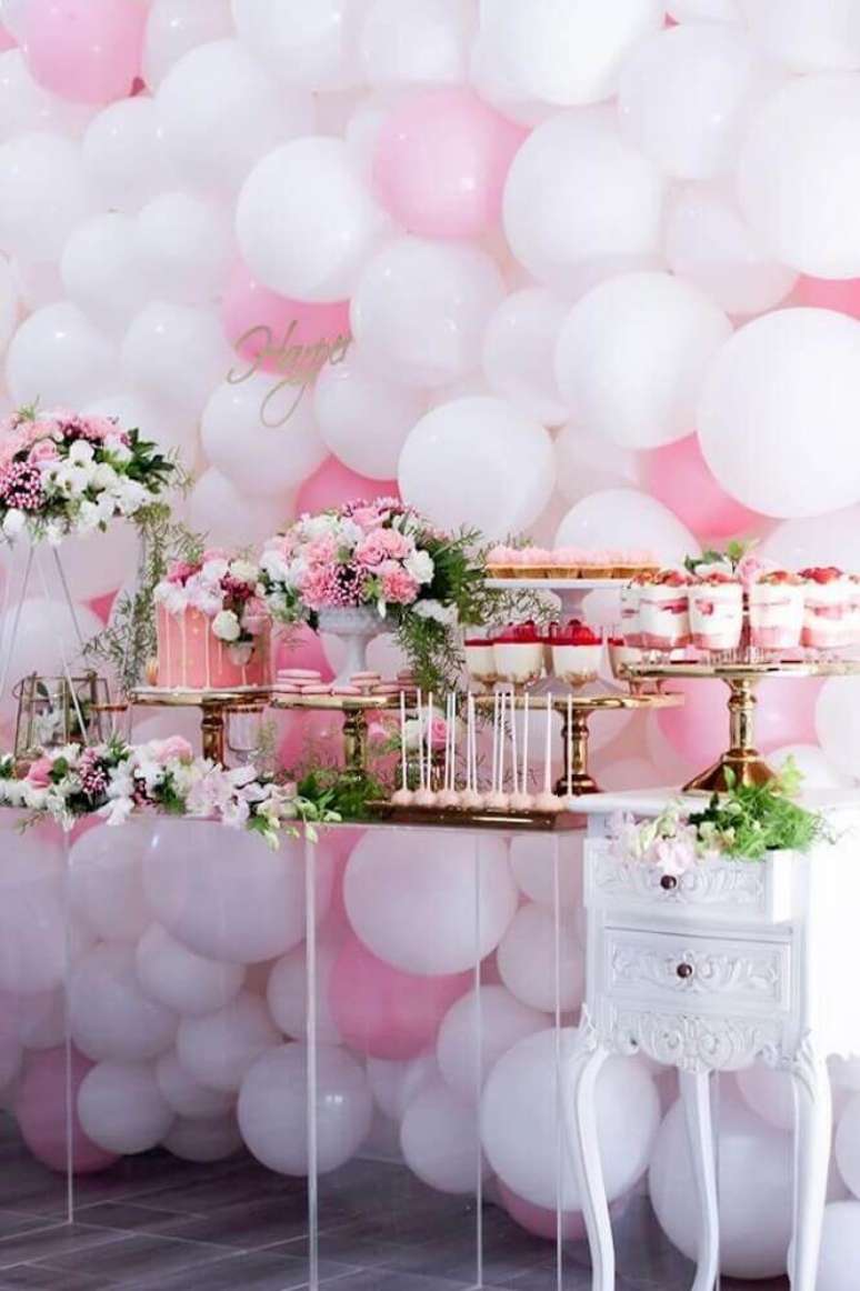 88. Festa decorada com bexigas rosa e branca e arranjo de flores na mesa do bolo – Foto: Pinterest