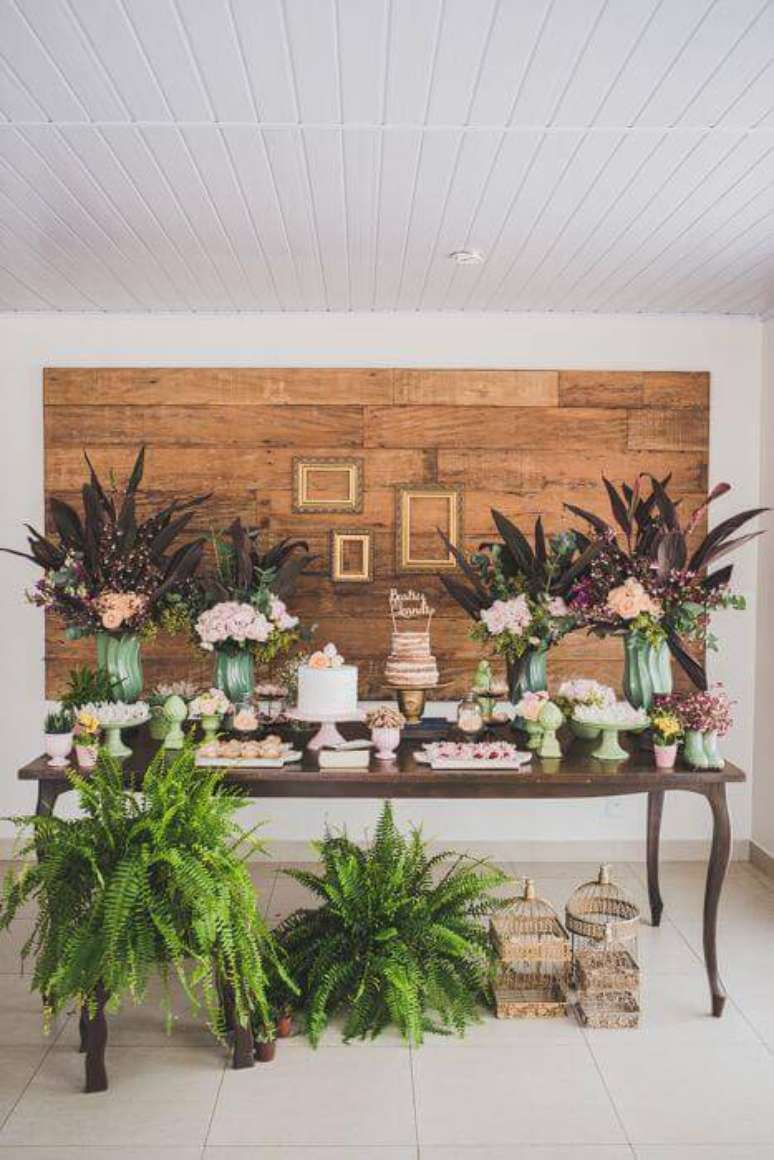 41. Uma mesa mais elegante &eacute; poss&iacute;vel com madeira, flores e folhagens na decora&ccedil;&atilde;o de festa.