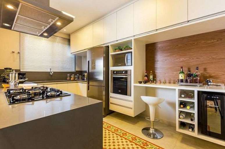 20. Aproveitar os armários de cozinha para fazer uma área para refeições rápidas é uma ideia criativa. Projeto por By Arquitetura.