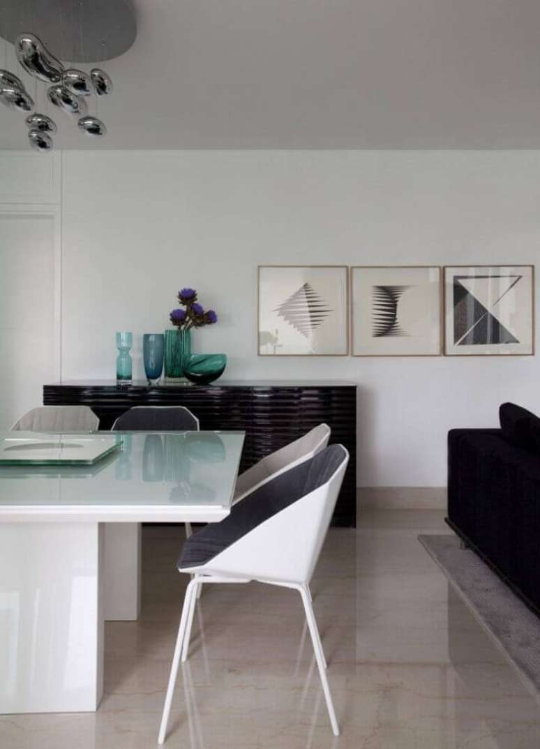 42. Decoração com buffet preto e cadeiras modernas para sala de jantar om mesa branca – Foto: Érica Salgueiro