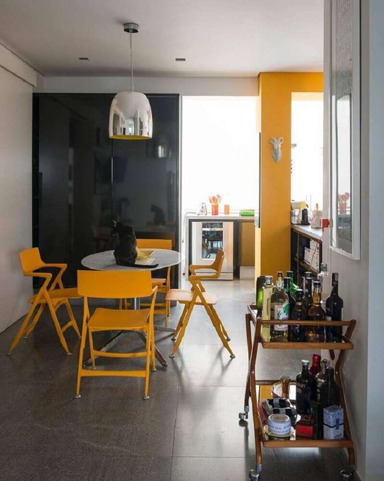 47. Decoração com pendente metálico e cadeiras amarelas para sala de jantar moderna – Foto: Antônio Ferreira Junior