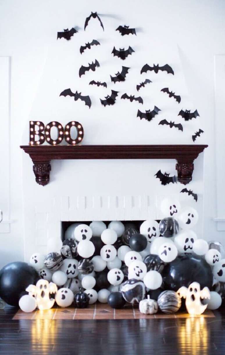 6. Linda decoração de Halloween com muitos balões saindo da lareira e morcegos na parede – Foto: MOODecor