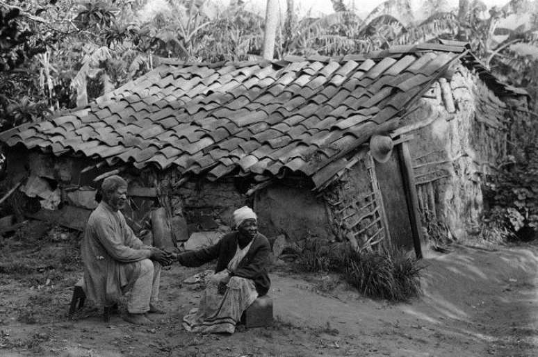 Casal de ex-escravos de mãos dadas em frente ao seu barraco, em Porto Alegre, em 1900