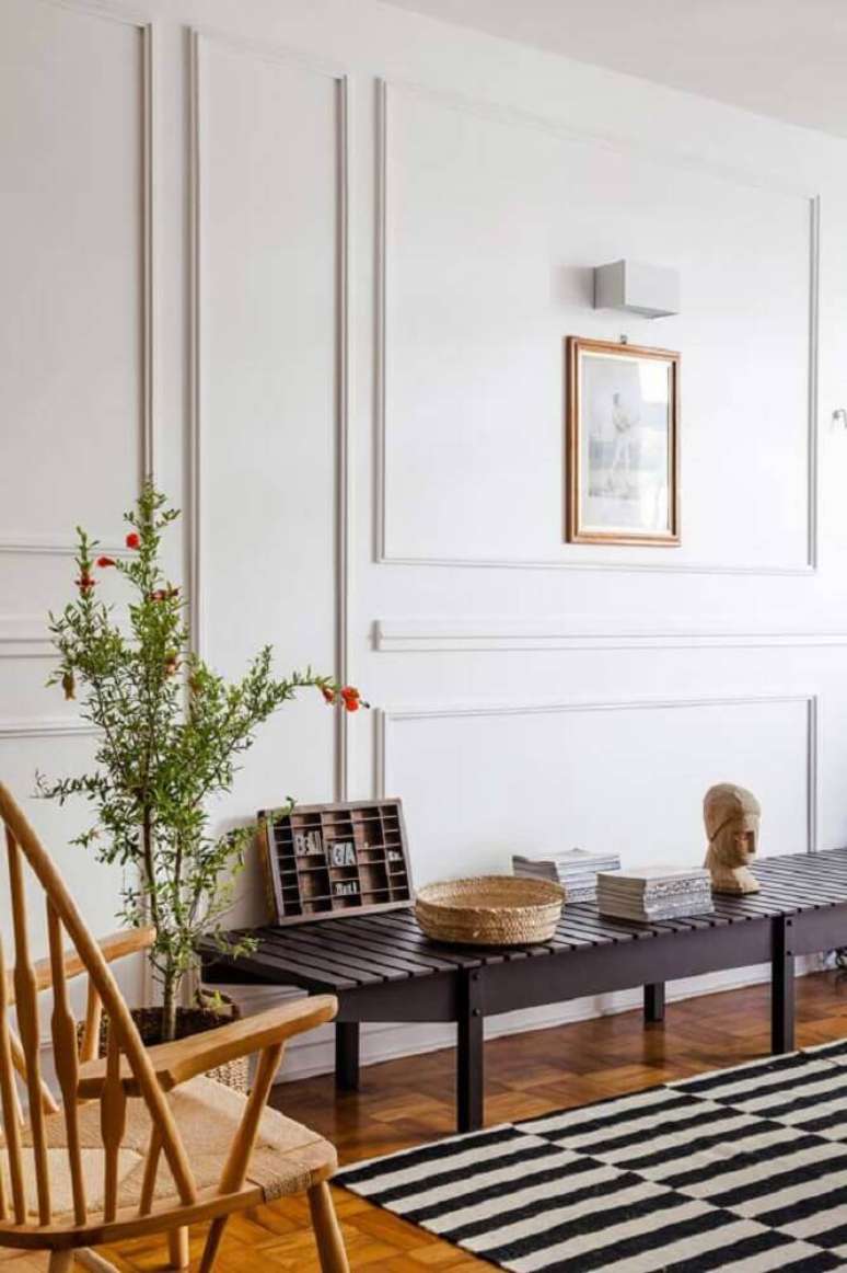 14. Decoração com tapete listrado, cadeira de madeira e parede com boiserie gesso – Foto: The Holk