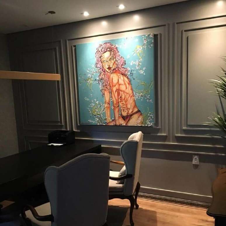 39. Decoração moderna para escritório com boiserie pintado de cinza e com grande quadro – Foto: Dayane Moreschi