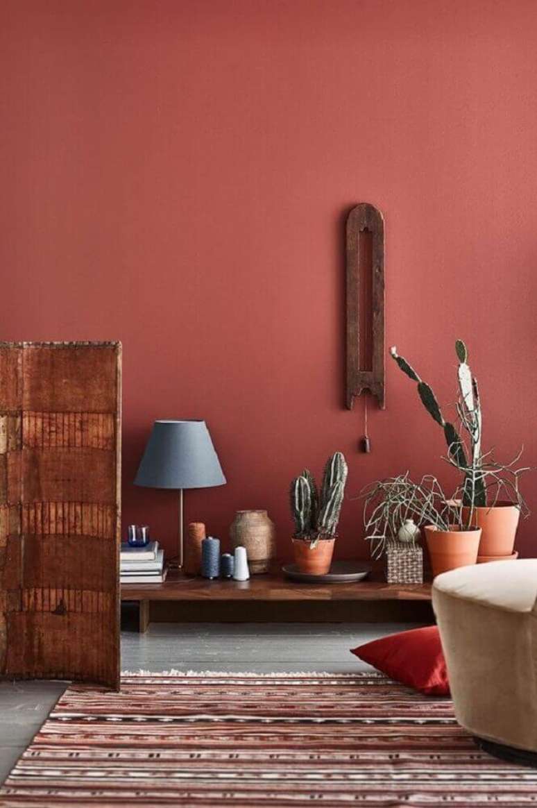 7. Ambiente decorado com tapete listrado, vasos de plantas e parede na cor damasco – Foto: Pinterest