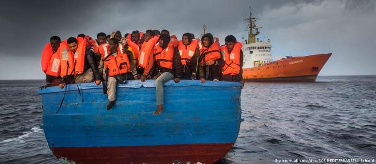 Migrantes são resgatados no Mar Mediterrâneo por uma equipe do navio Aquarius (ao fundo)