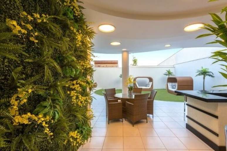 34. Quintal com jardim vertical com flores amarelas. Projeto de Iara Kilaris