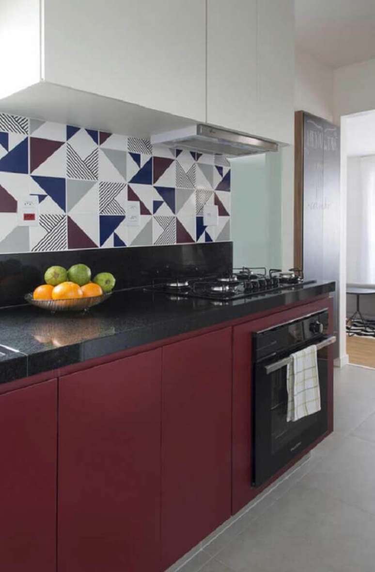 27. Decora&ccedil;&atilde;o com arm&aacute;rio planejado de cozinha branco e vinho e azulejos estampados &ndash; Foto: SP Est&uacute;dio