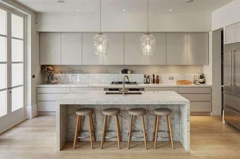 29. Cozinha com ilha decorada com arm&aacute;rio de cozinha planejado cinza e pendentes de vidro sobre a ilha &ndash; Foto: Mujer Hoy