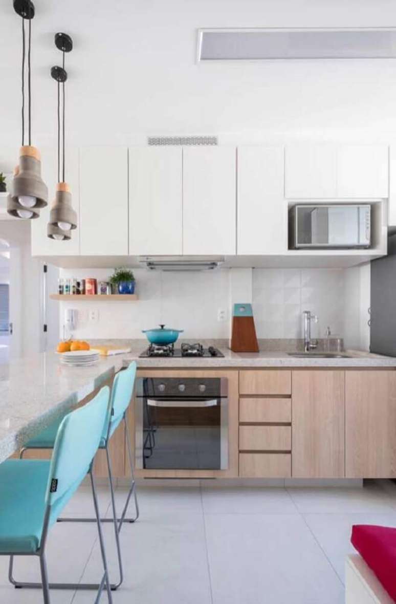 36. Cozinha decorada com cadeiras azuis, pendentes modernos e armário de cozinha planejado branco – Foto: Pinterest