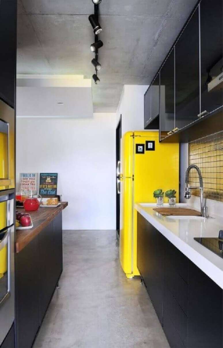 40. Modernidade para cozinha com armário de cozinha planejado preto e geladeira amarela – Foto: IBD Arquitetura