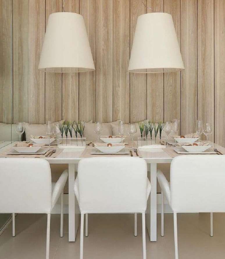 18. A madeira como revestimento de parede deixa a sala de jantar moderna com pendentes sobre a mesa muito mais aconchegante – Foto: Mariana Orsi