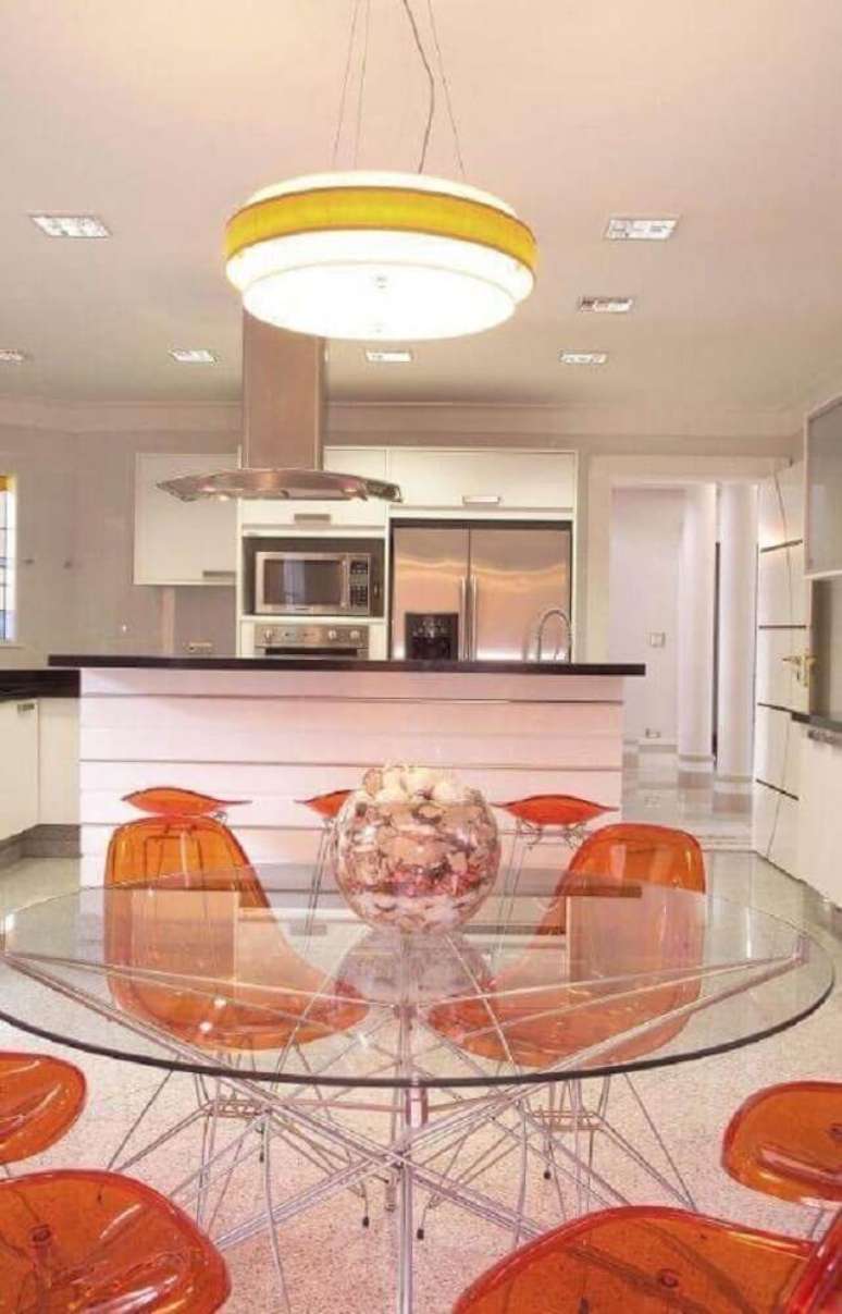 37. Decoração de sala de jantar moderna com mesa redonda de vidro e cadeiras plásticas laranjas – Foto: Aquiles Nicolas Kilaris