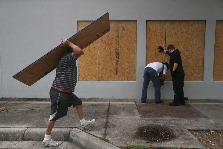 Moradores colocam madeira compensada para proteger construções em Port St. Joe, na Flórida