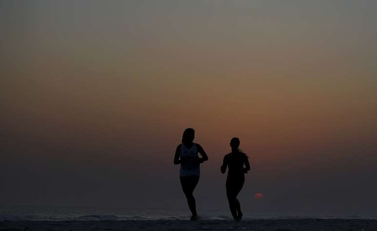 Mulheres correm durante o pôr do sol na praia da Barra da Tijuca, no Rio de Janeiro 20,/10/2015. REUTERS/Sergio Moraes 