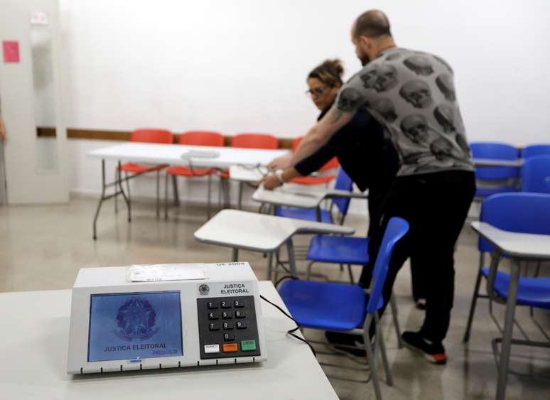 Funcionários preparam urna eletrônica em seção eleitoral em São Paulo