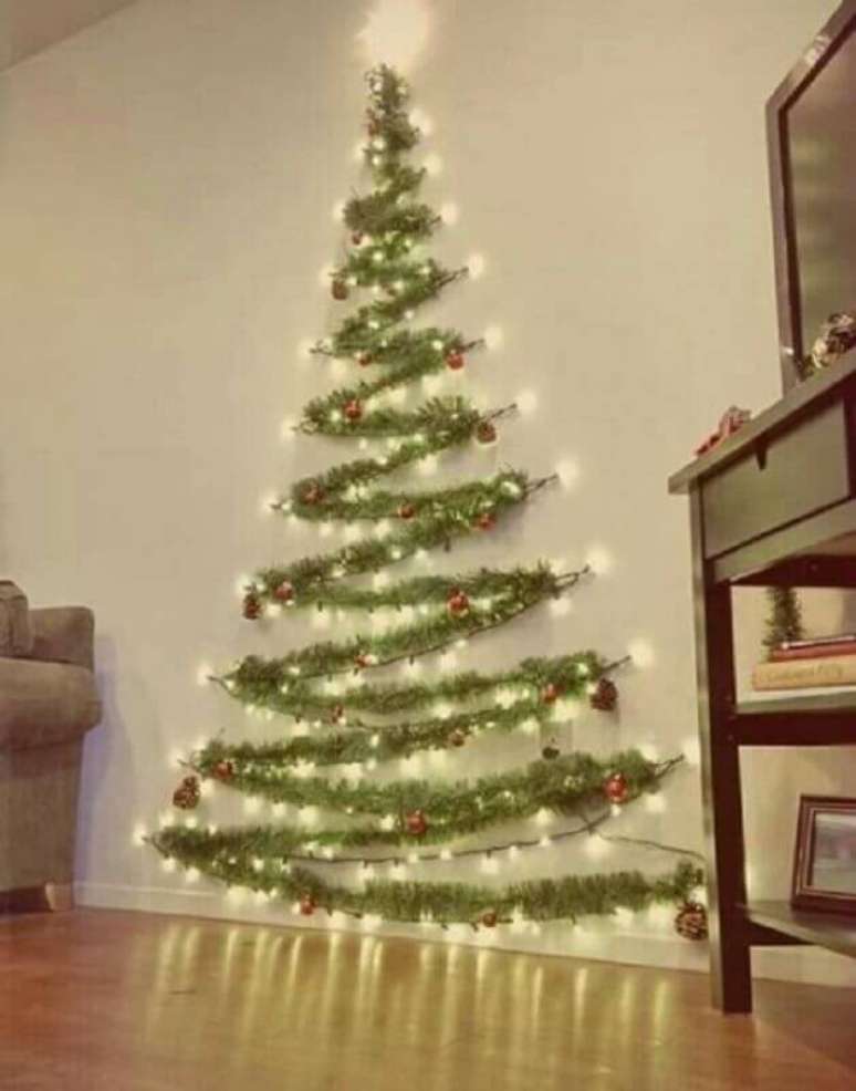 14. Se você mora em um apartamento pequeno é possível fazer um árvore de natal que não vai ocupar muito espaço, para isso você precisa de festão e luzes de natal – Foto: Her Campus