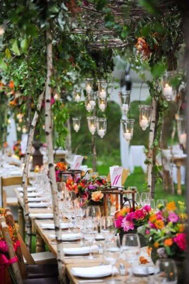 52. Festa externa com tema jardim encantado e mesas longas com decorações de flores e folhas. Foto de Pinterest