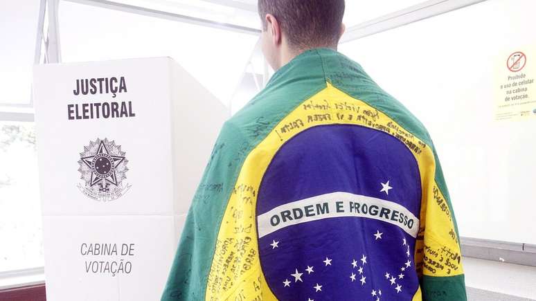 Homem envolvo em uma bandeira do Brasil se dirige &agrave; cabina de vota&ccedil;&atilde;o, em Belo Horizonte, Minas Gerais