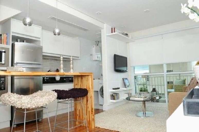 38. Decoração simples para cozinha integrada com sala de estar com bancada de madeira e armários brancos – Foto: Pinterest