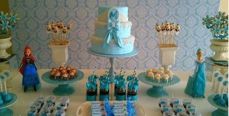 26- Na festa Frozen ideias criativas o bolo foi confeitado com pasta americana azul. Fonte: Mães Comadre