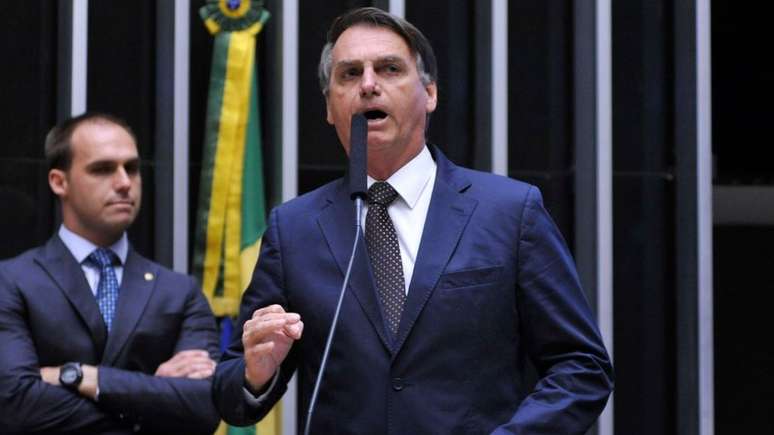 Jair Bolsonaro (à frente, à dir.) e seu filho Eduardo Bolsonaro (à esq., atrás), no plenário da Câmara