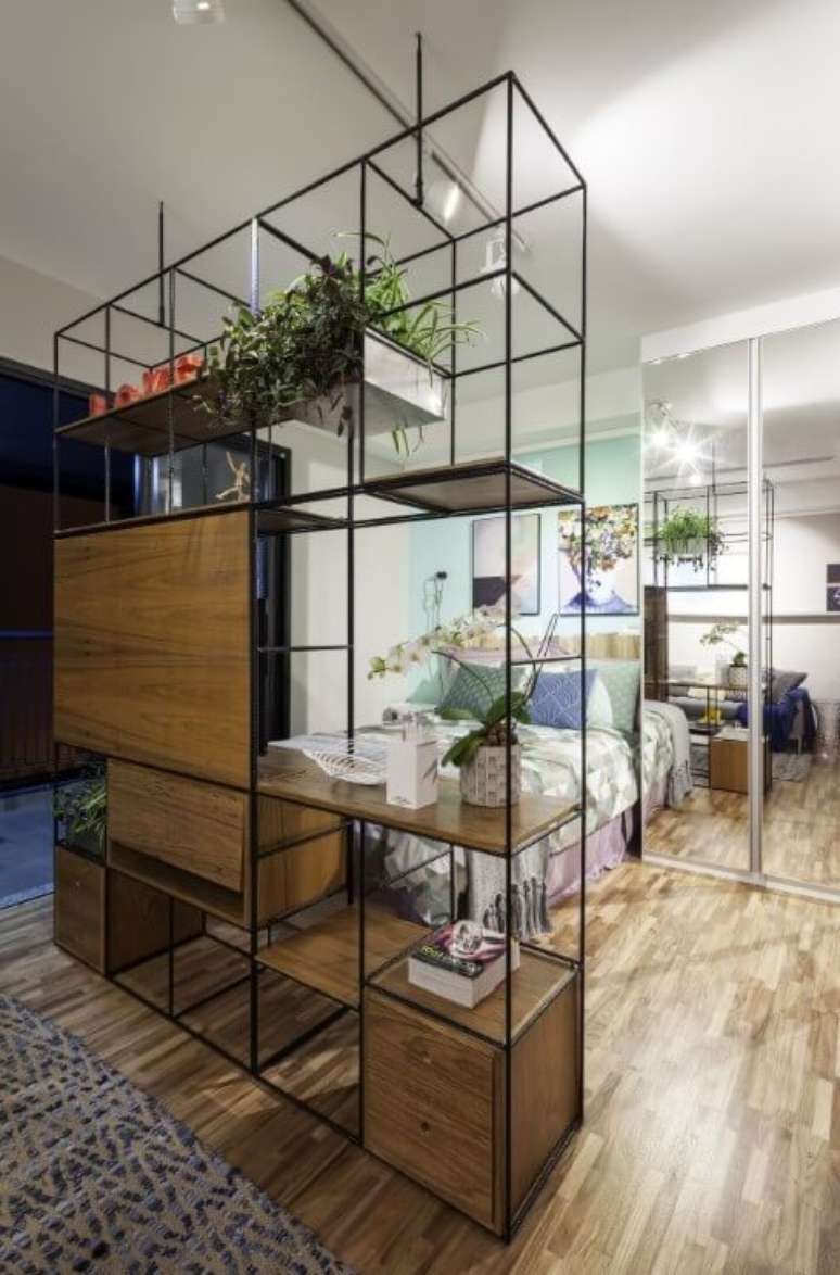 14. Apartamento pequeno decorado com estante modular separando o quarto da sala. Projeto de Decoradoria Decoração Online