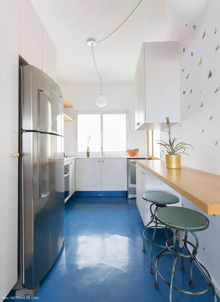 10. Decoração simples para cozinha com piso azul, armários brancos e bancada de madeira – Foto: The Holk