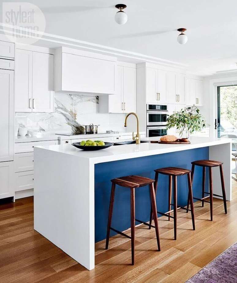 57. Decoração clean para cozinha planejada com ilha azul e banquetas de madeira – Foto: Style at Home