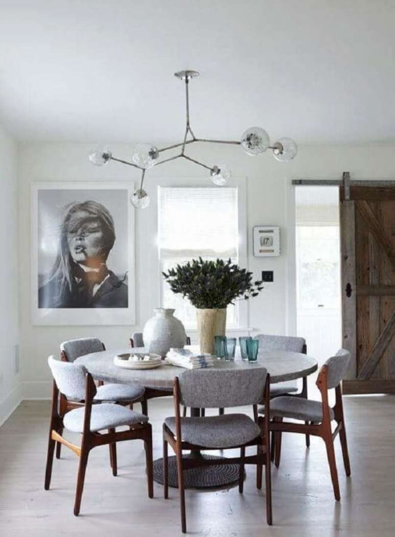 42. Decoração minimalista para sala de jantar com mesa redonda e luminária de teto diferente – Foto: Pinterest