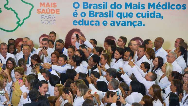 Programa Mais Médicos foi criado pelo governo de Dilma Rousseff - na imagem, tirada em 2016, Dilma lança nova fase do programa e é cercada por profissionais, alguns cubanos
