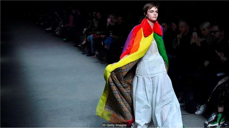 Cara Delevingne desfilou usando a capa de arco-íris da Burberry, feita com pele artificial, peça que foi destaque no desfile outono/inverno de Londres