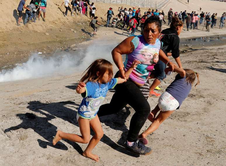 Fam&iacute;lia de Honduras corre para fugir do g&aacute;s lacrimog&ecirc;neo na fronteira do M&eacute;xico com os Estados Unidos em Tijuana 25/11/2018 REUTERS/Kim Kyung-Hoon