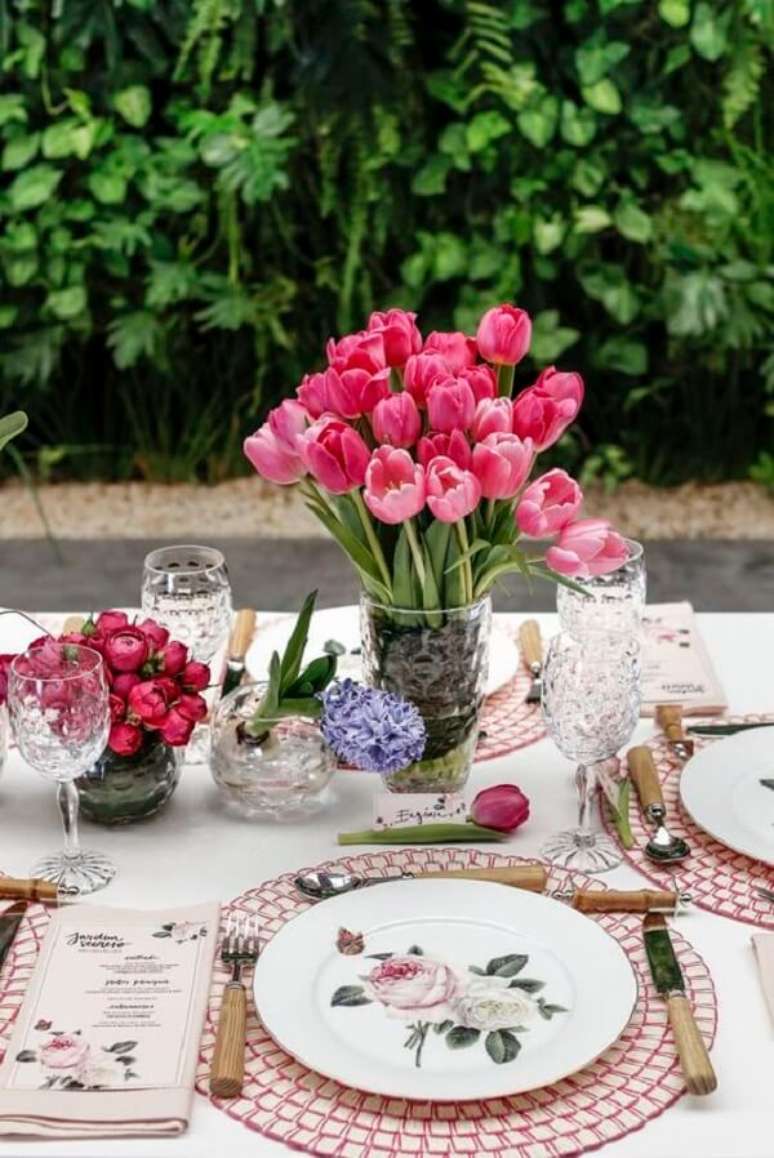 59- A mesa posta para varanda utiliza taças de cristal para água, talheres com cabos de madeira, louças e guardanapos com padrões florais. Fonte: Vamos Receber