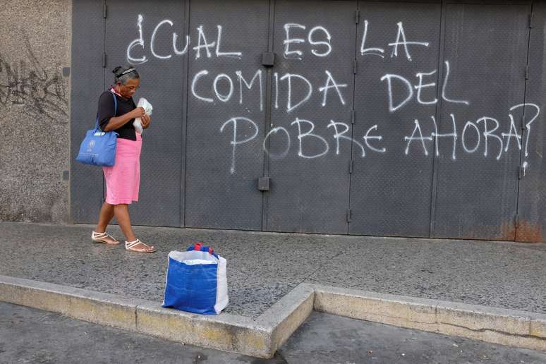 Mulher anda em frente a pichação de protesto em Caracas