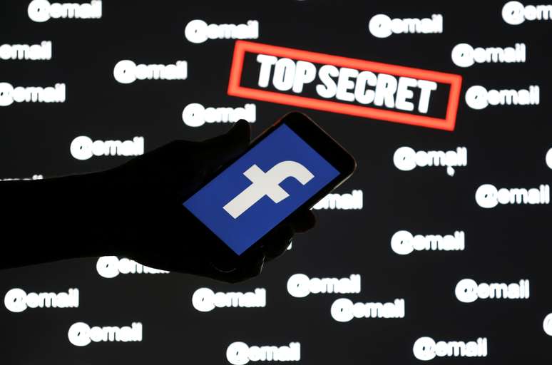  Uma pessoa segura um smartphone com o logotipo do Facebook na frente das palavras exibidas "ultra secreto" e "email" 6/12/ 2018. REUTERS/Dado Ruvic