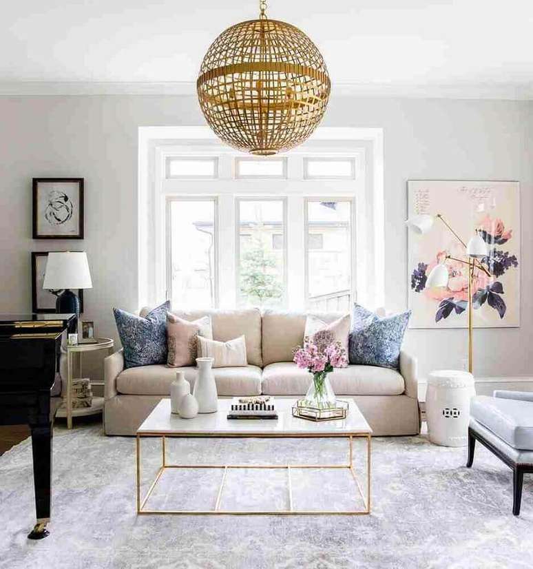 29. Decora&ccedil;&atilde;o sofisticada em tons de rosa e dourado com enfeites decorativos para sala com pendente redondo &ndash; Foto: Diseno Interior