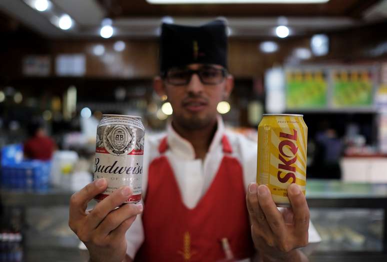 Garçom segura latas de cervejas fabricadas pela Ambev dentro de bar em São Paulo. 25/07/2018. REUTERS/Nacho Doce.