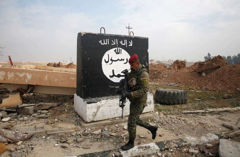 Soldado iraquiano passa por painel pintado com bandeira preta do Estado Islâmico em Mosul 21/01/2017  REUTERS/Khalid al Mousily